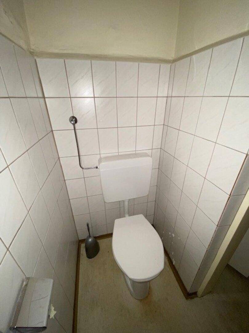 Kleines Gäste-WC mit weißen Fliesen und einfacher Toilette, in gutem Zustand.