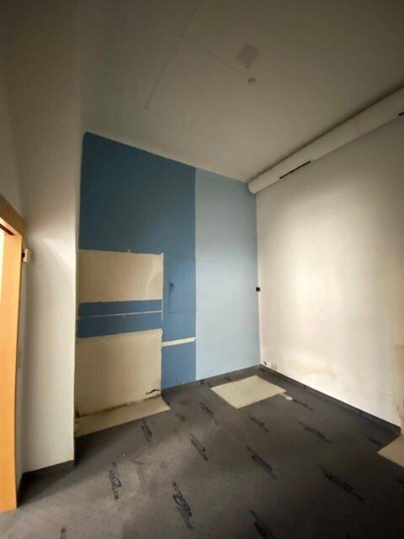 Renovierungsbedürftiger Raum mit blauer Wandfarbe und vorbereitetem Bodenbelag.