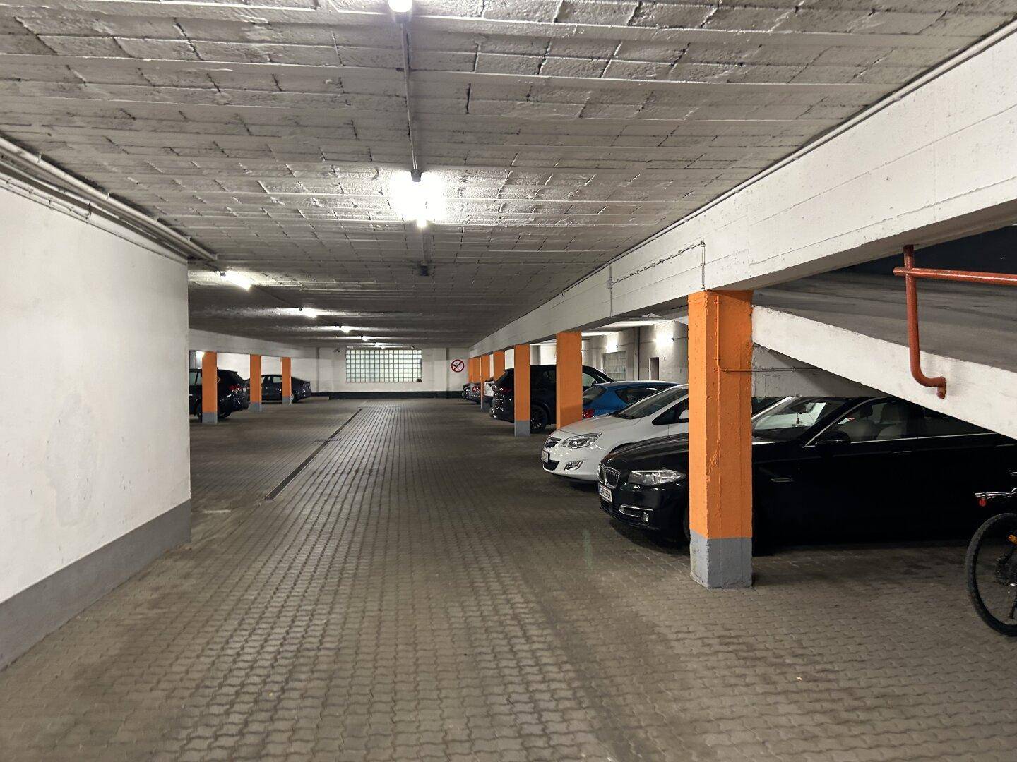 Tiefgarage mit orangefarbenen Stützpfeilern und geparkten Autos.
