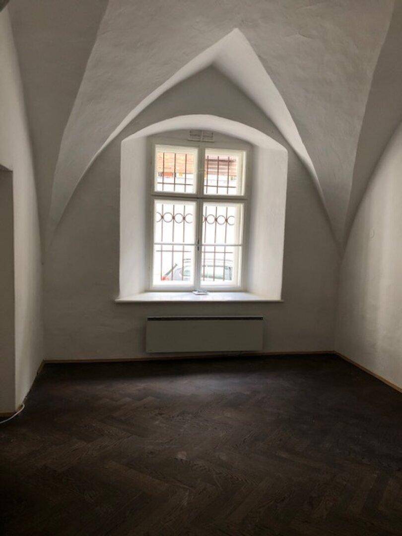 Raum mit markanten Gewölbedecken, einem einzigartigen Bogenfenster mit Gitter und dunklem Fischgrätparkett.