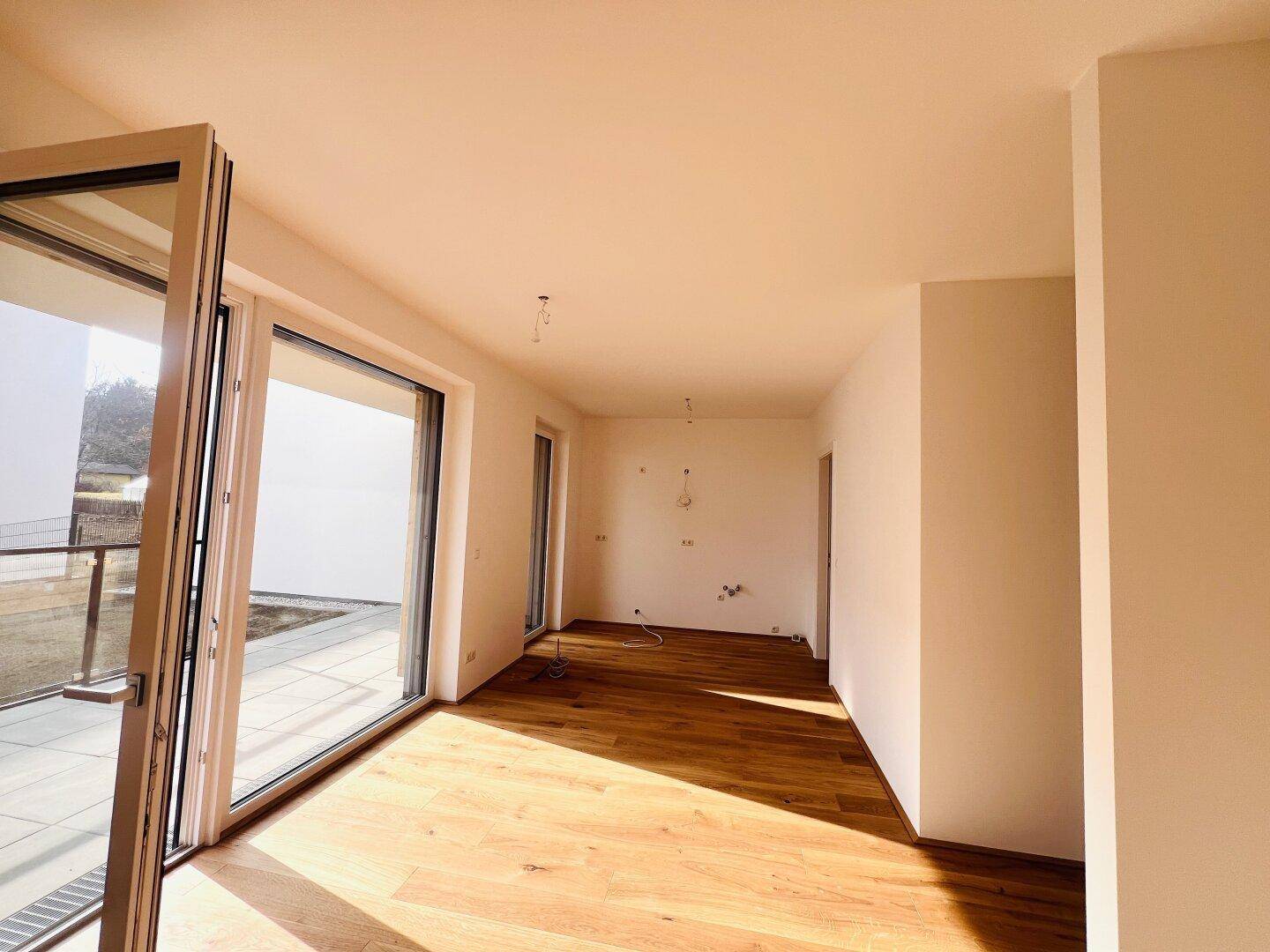 Lichtdurchfluteter Raum mit neuem Holzboden und direktem Zugang zu einem Außenbereich.