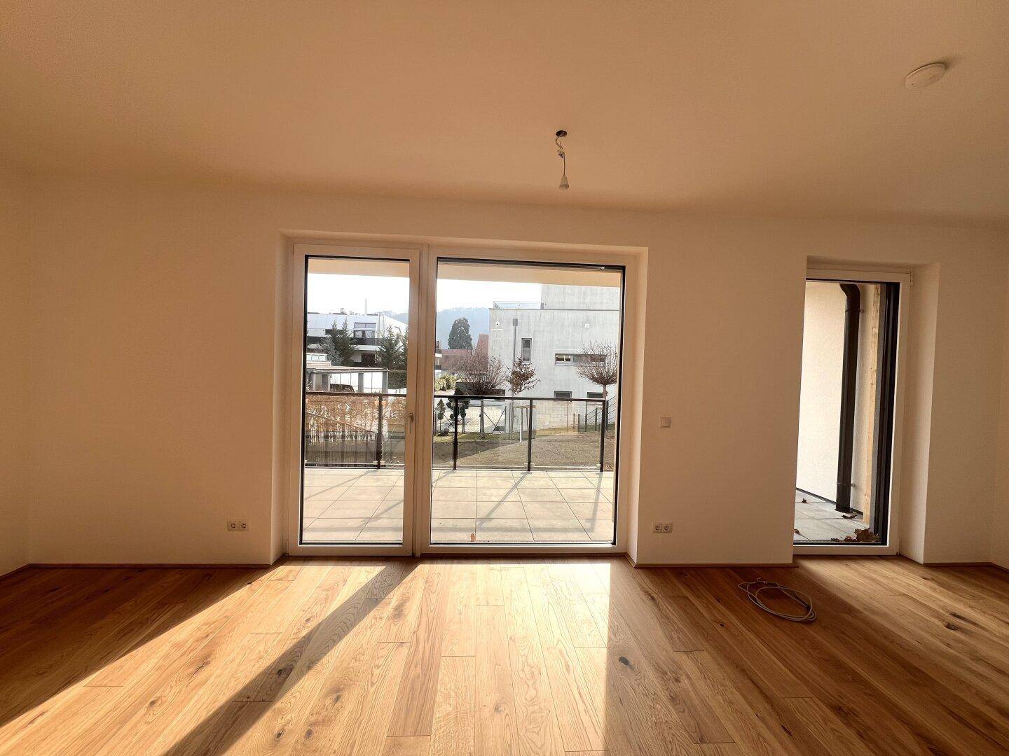 Helles Wohnzimmer mit neuem Parkettboden und Zugang zu einer großzügigen Terrasse.