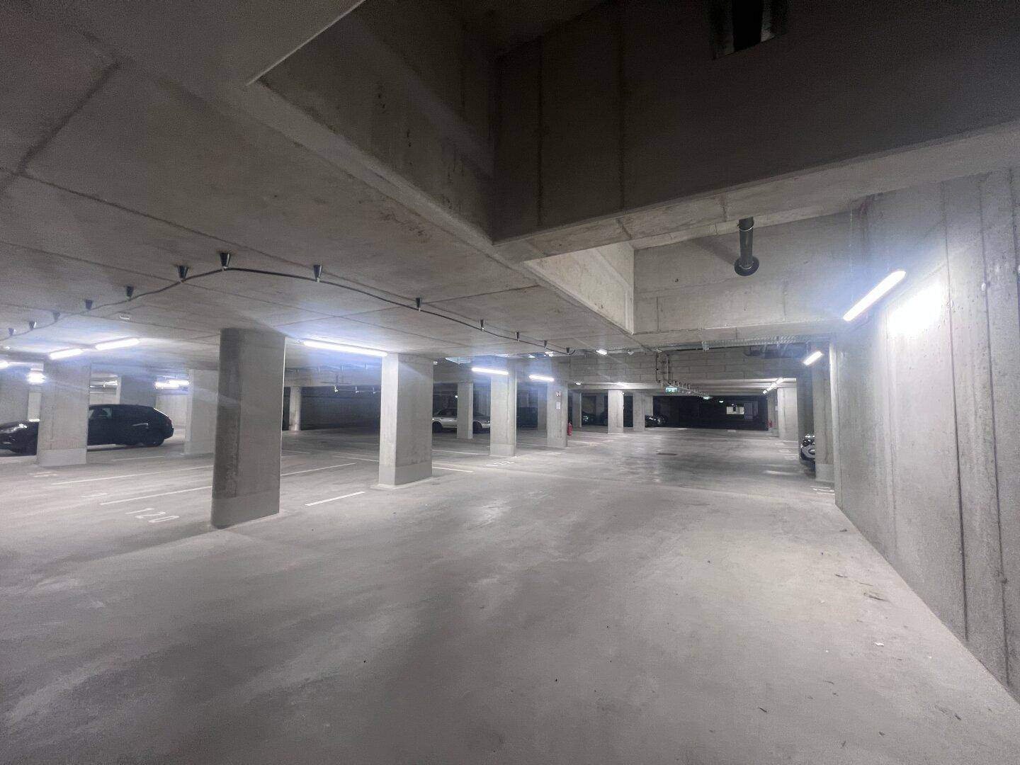 Geräumige Tiefgarage mit vielen Stellplätzen und guter Beleuchtung im Untergeschoss.