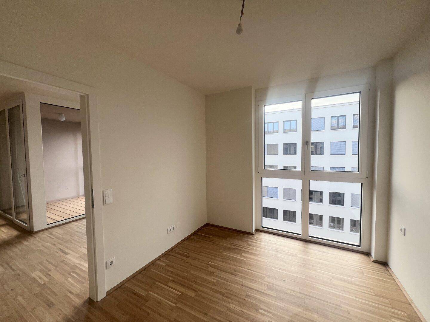 Helles Zimmer mit großem Fenster und Parkettboden, ideal als Schlaf- oder Arbeitszimmer.