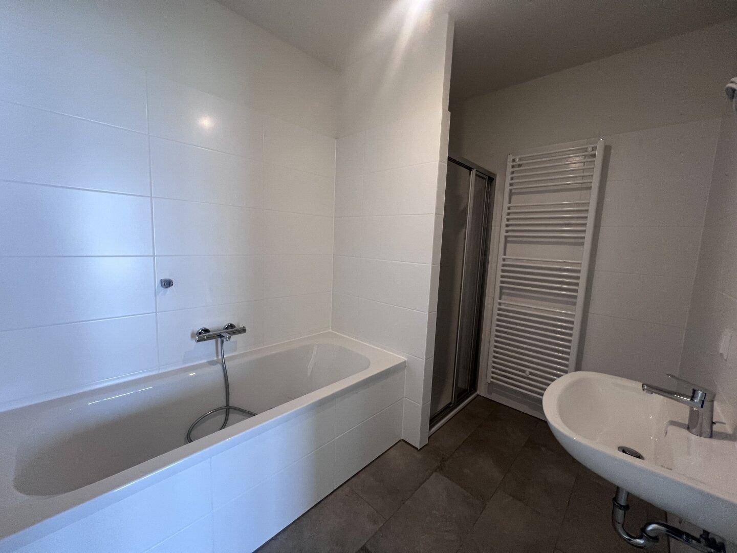 Modernes Badezimmer mit Badewanne, Dusche und weiß gefliesten Wänden.