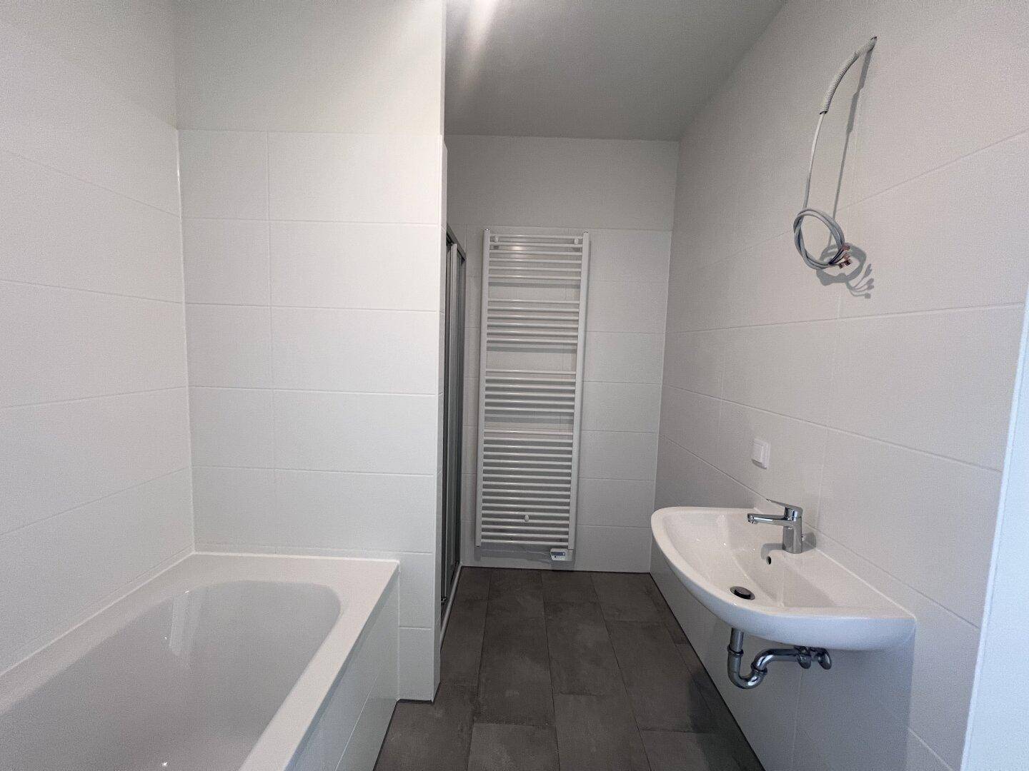 Helles Badezimmer mit modernem Waschbecken, Dusche und beheiztem Handtuchhalter.
