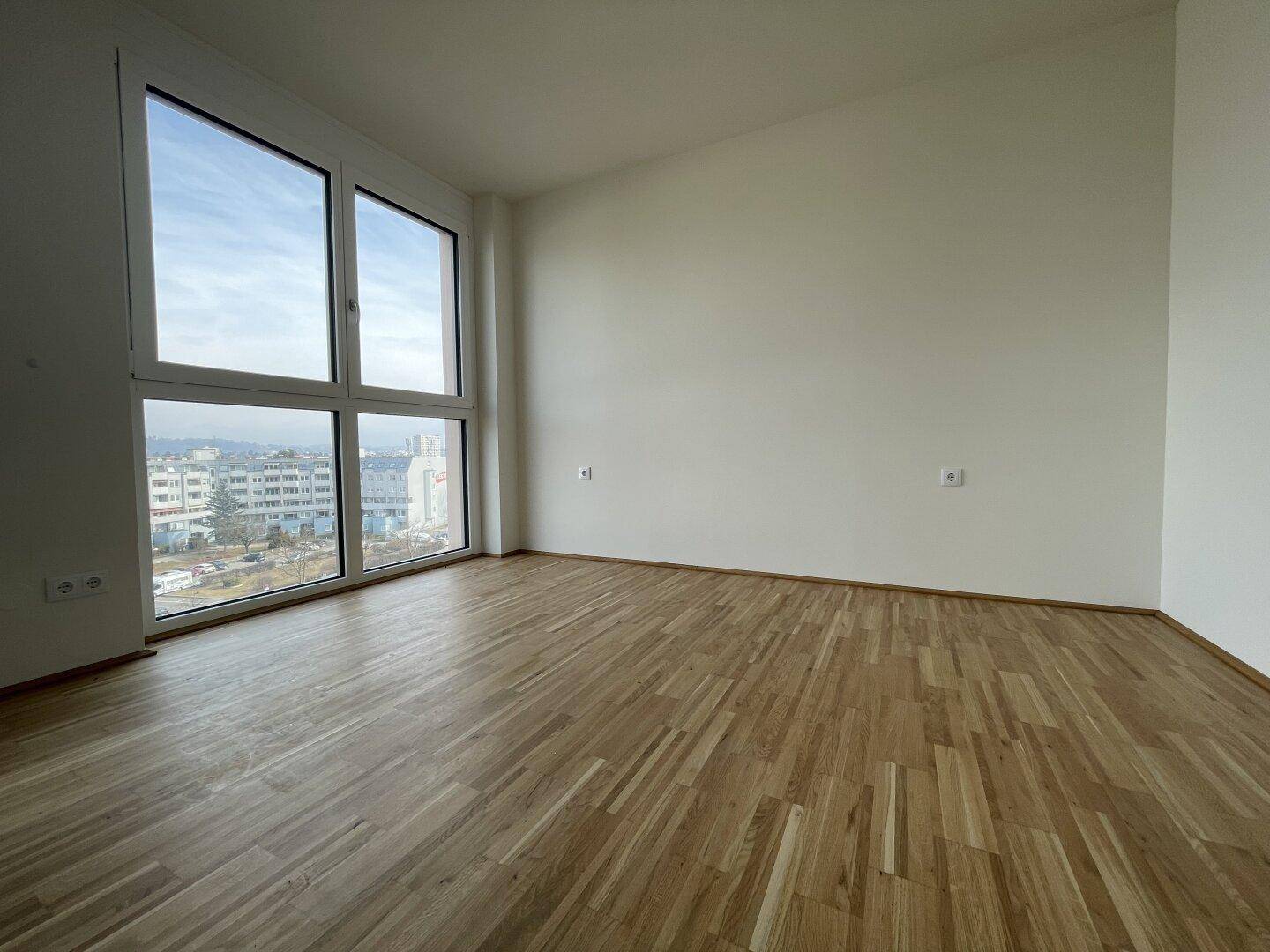 Geräumiges, helles Zimmer mit Holzboden und weitem Blick über die Stadt.