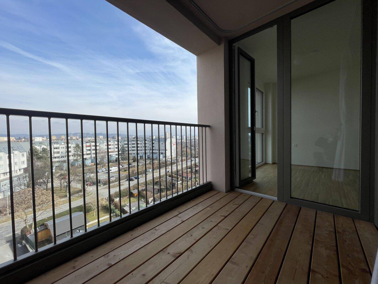 Breiter Balkon mit Holzdielen und Panoramablick über die Stadtlandschaft.