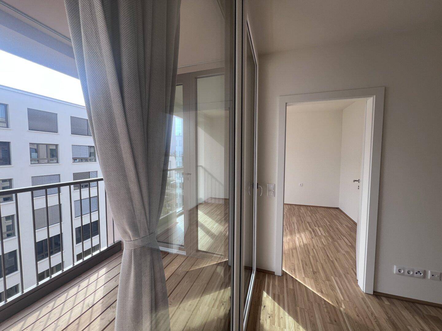 Lichtdurchfluteter Raum mit Parkettboden und direktem Zugang zum Balkon, bietet viel Helligkeit.