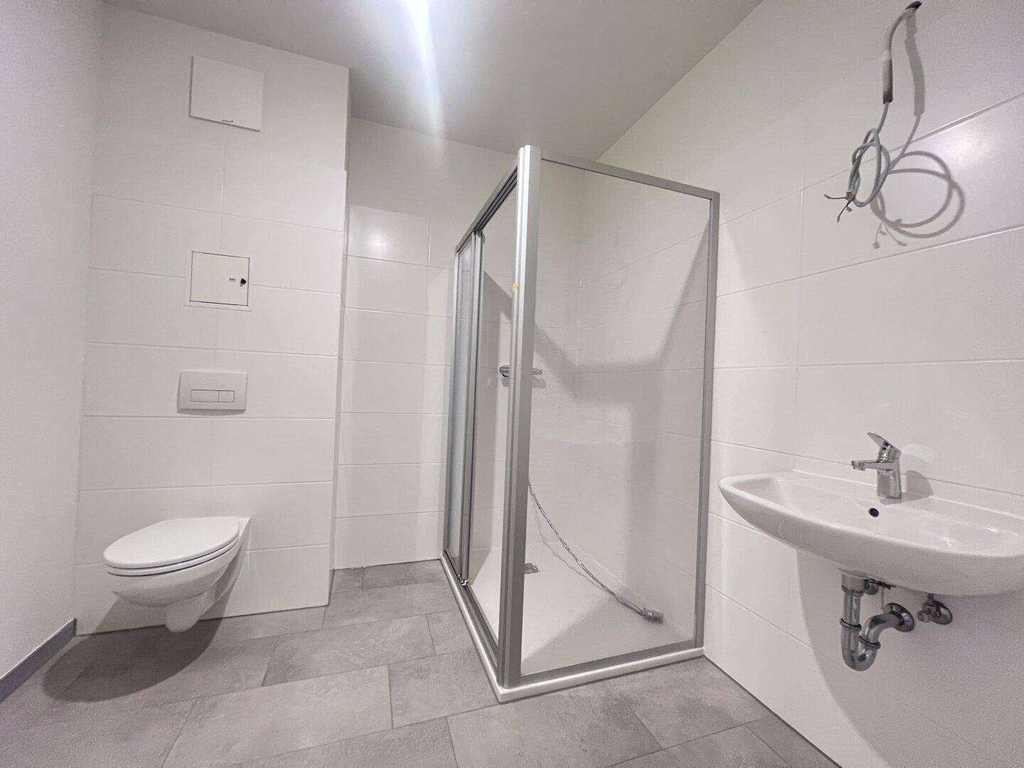 Helles Badezimmer mit Dusche, WC und Waschbecken, in modernem und funktionalem Design.