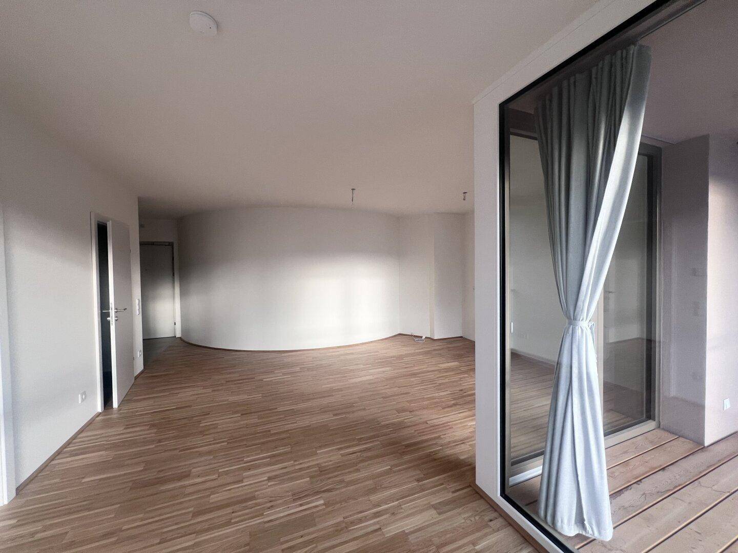 Offener Wohnbereich mit elegantem Parkettboden und Zugang zum Außenbereich.