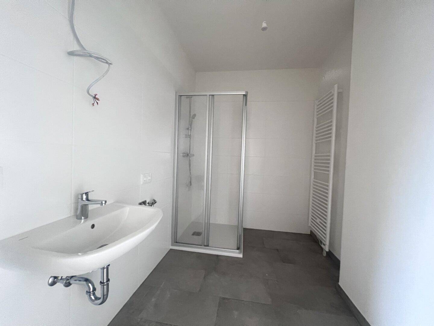 Modernes Badezimmer mit Dusche, Waschbecken und praktischem Handtuchheizkörper.