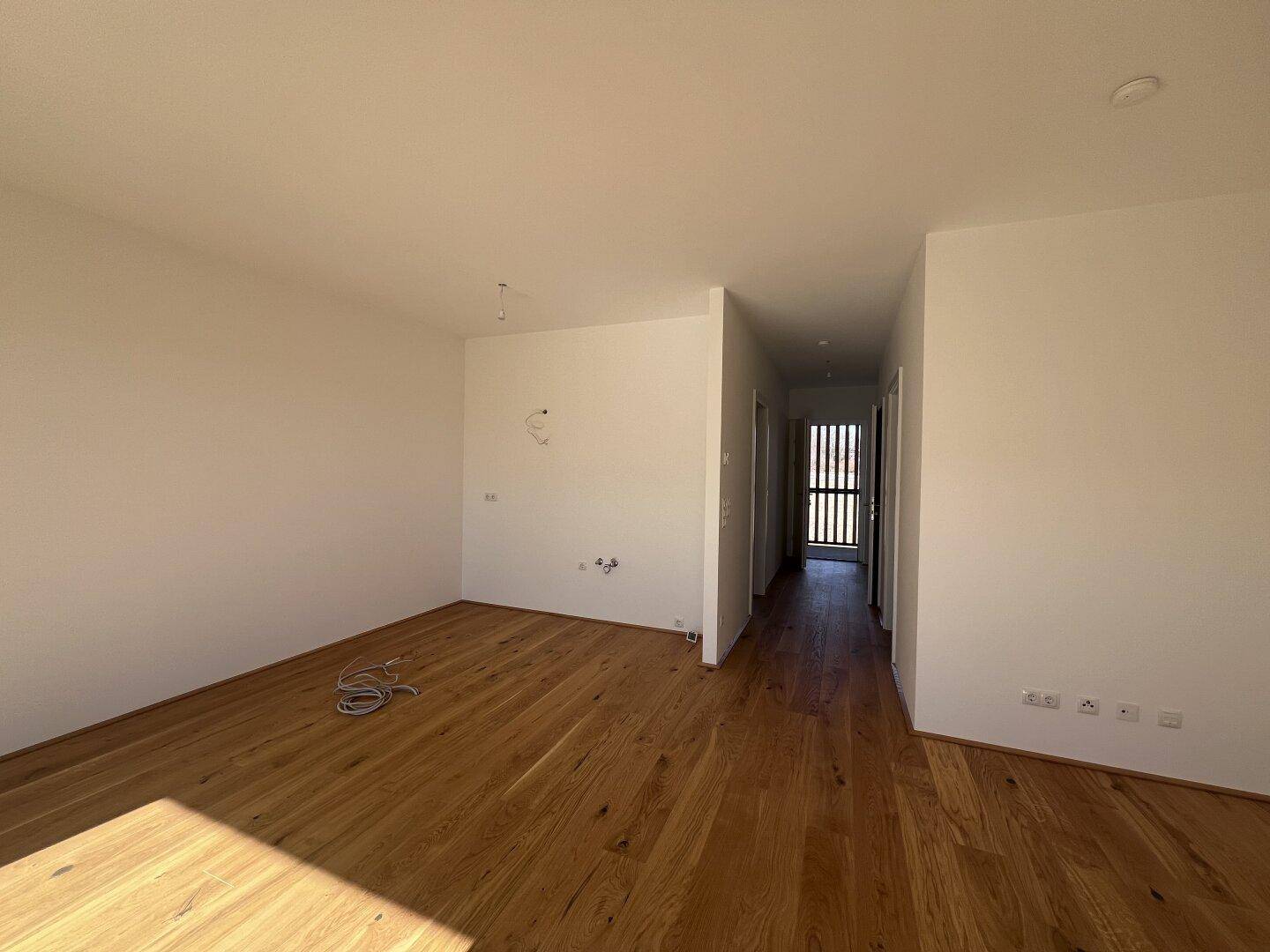 Heller Flur mit Holzboden, der zu weiteren Räumen der Wohnung führt.