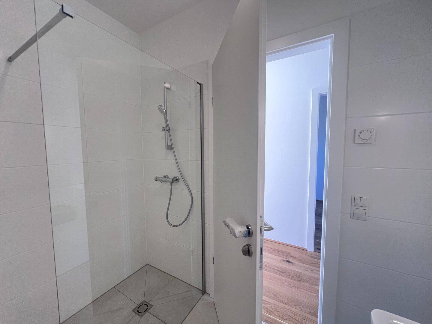 Modernes Badezimmer mit weiß gefliesten Wänden und einer begehbaren Dusche.