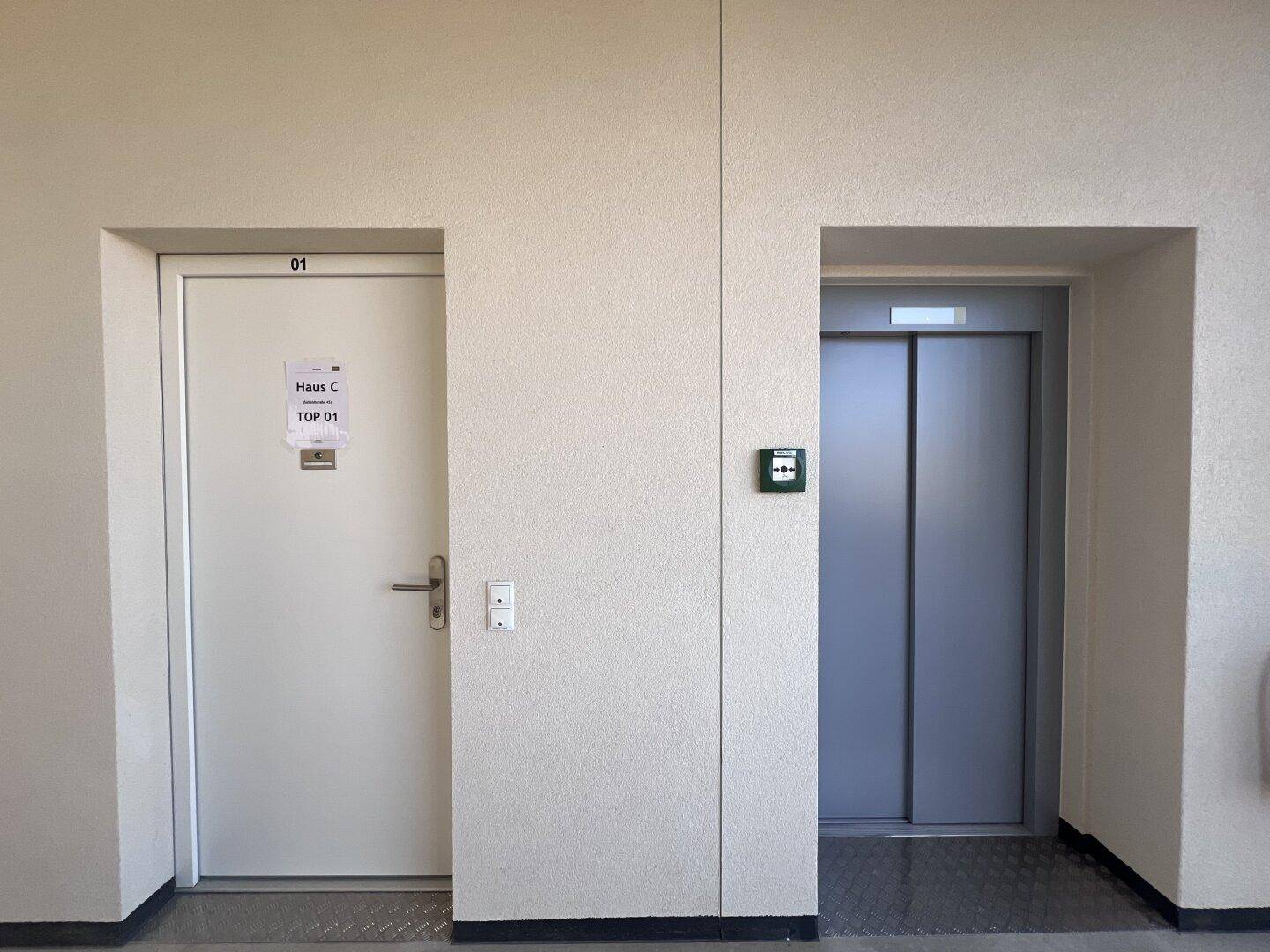 Flur im Gebäude mit Zugang zu einer Wohnung und einem modernen Aufzug für bequemen Zugang.