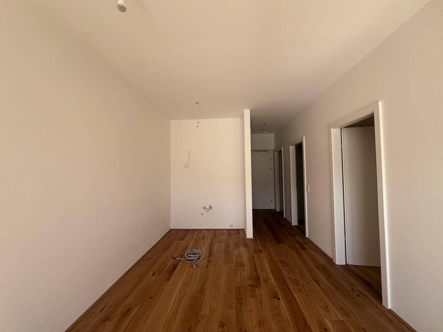 Heller Flur mit Holzboden und Zugang zu verschiedenen Zimmern, noch im Bau.