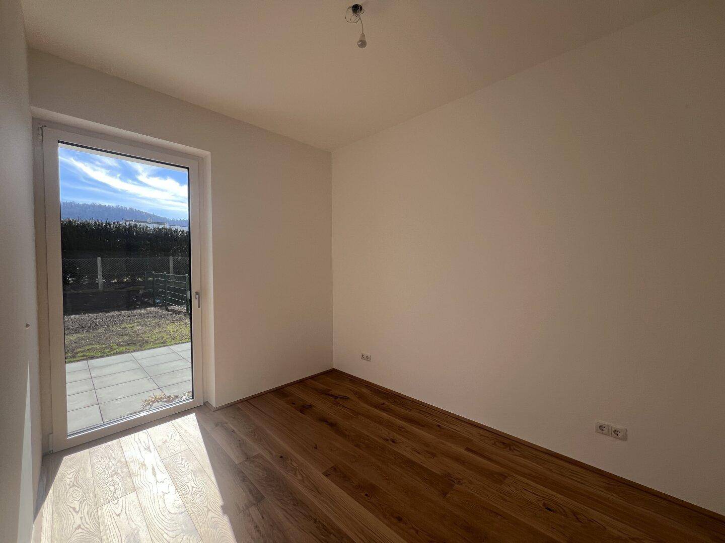 Helles Zimmer mit Holzboden und direktem Zugang zur Außenterrasse oder zum Gartenbereich.