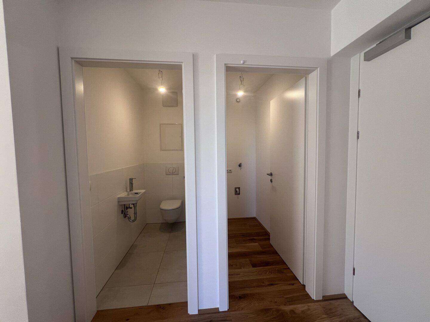 Heller Flurbereich mit Holzboden und Zugang zu einem modernen Gäste-WC.