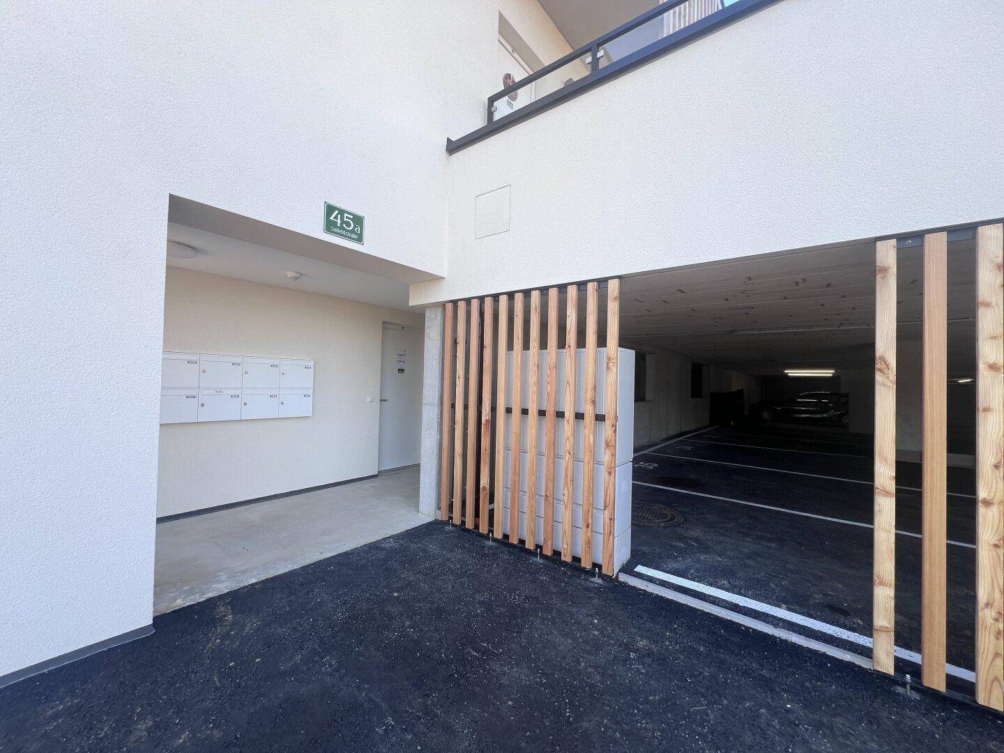 Eingangsbereich zur Tiefgarage mit moderner Fassade und Briefkästen.