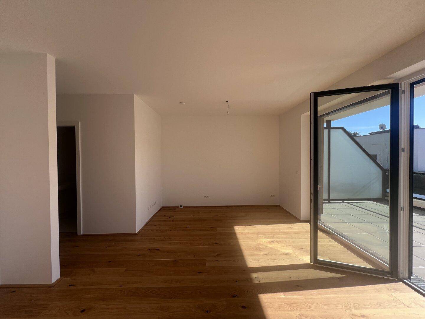 Heller Wohnraum mit neuem Parkettboden und Zugang zur sonnigen Terrasse.