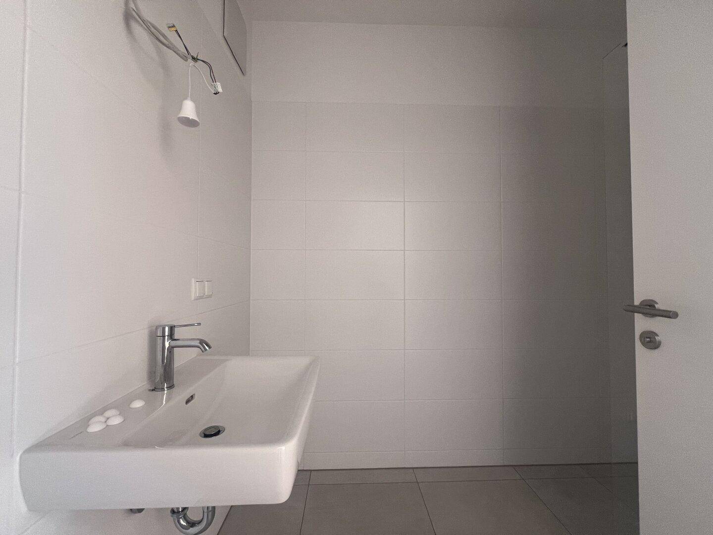 Modernes Badezimmer mit weiß gefliesten Wänden und einem einzelnen Waschbecken.