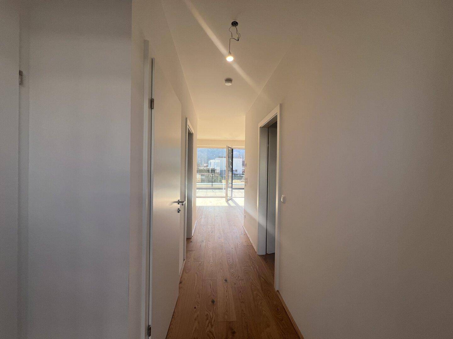 Heller Flur mit Parkettboden, der zu den verschiedenen Räumen und zum Balkon führt.