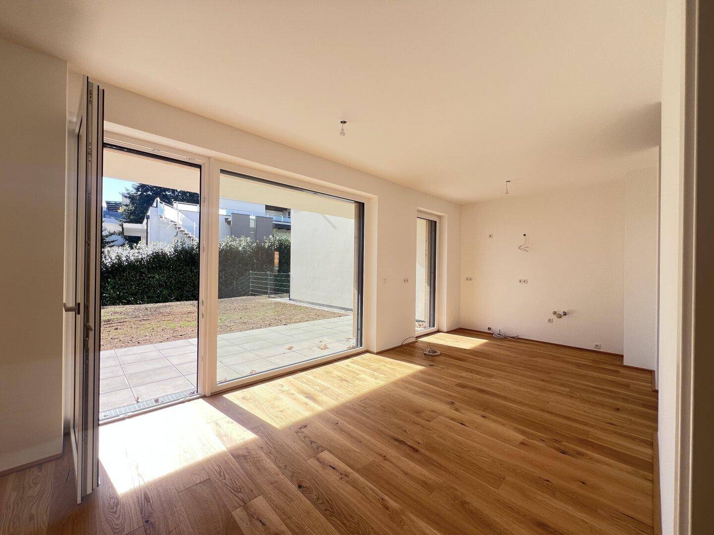Lichtdurchfluteter Wohnbereich mit Holzboden und direktem Zugang zum Außenbereich.