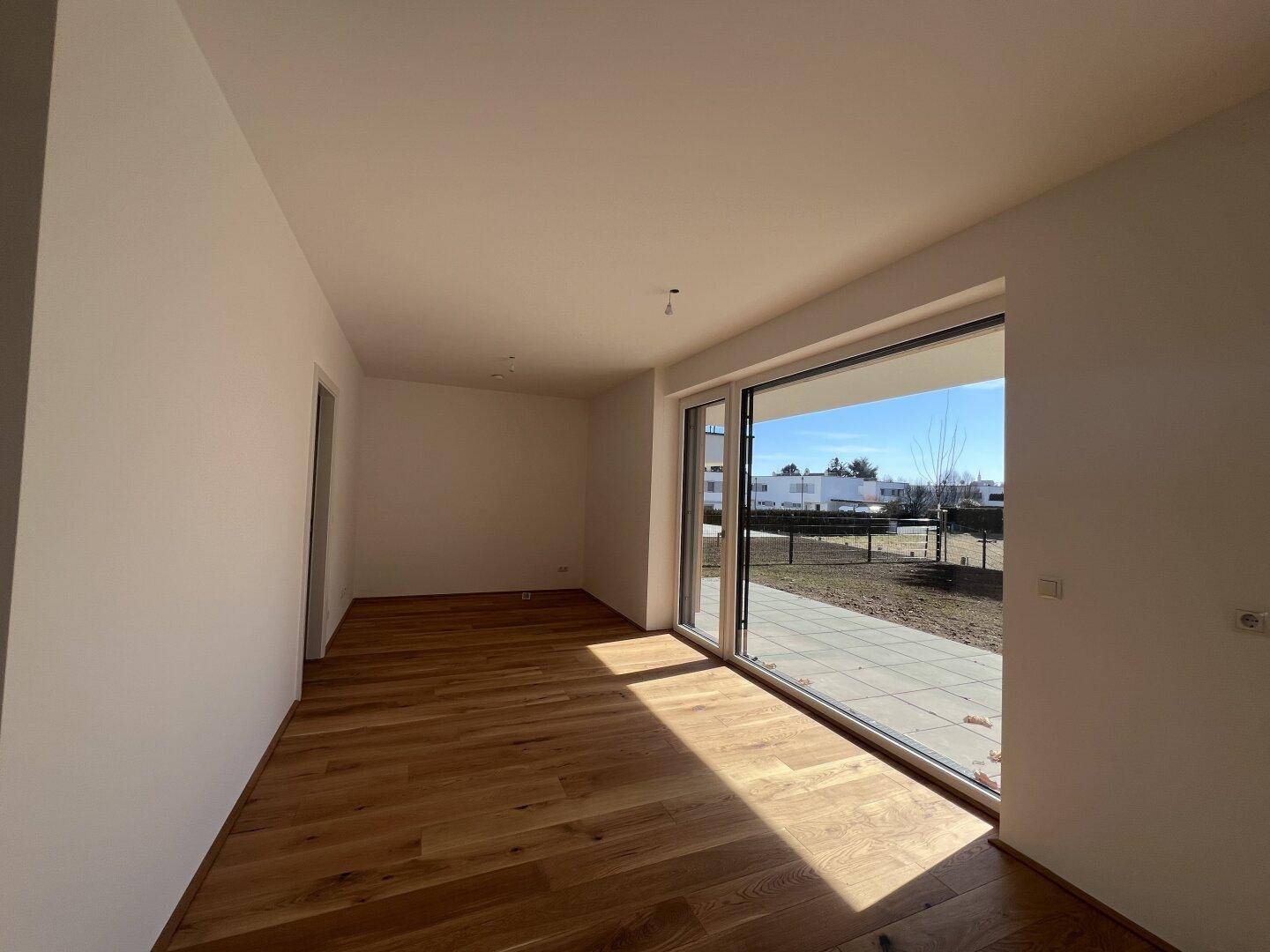 Geräumiger, heller Wohnraum mit Holzboden und weitem Blick durch große Fenster.