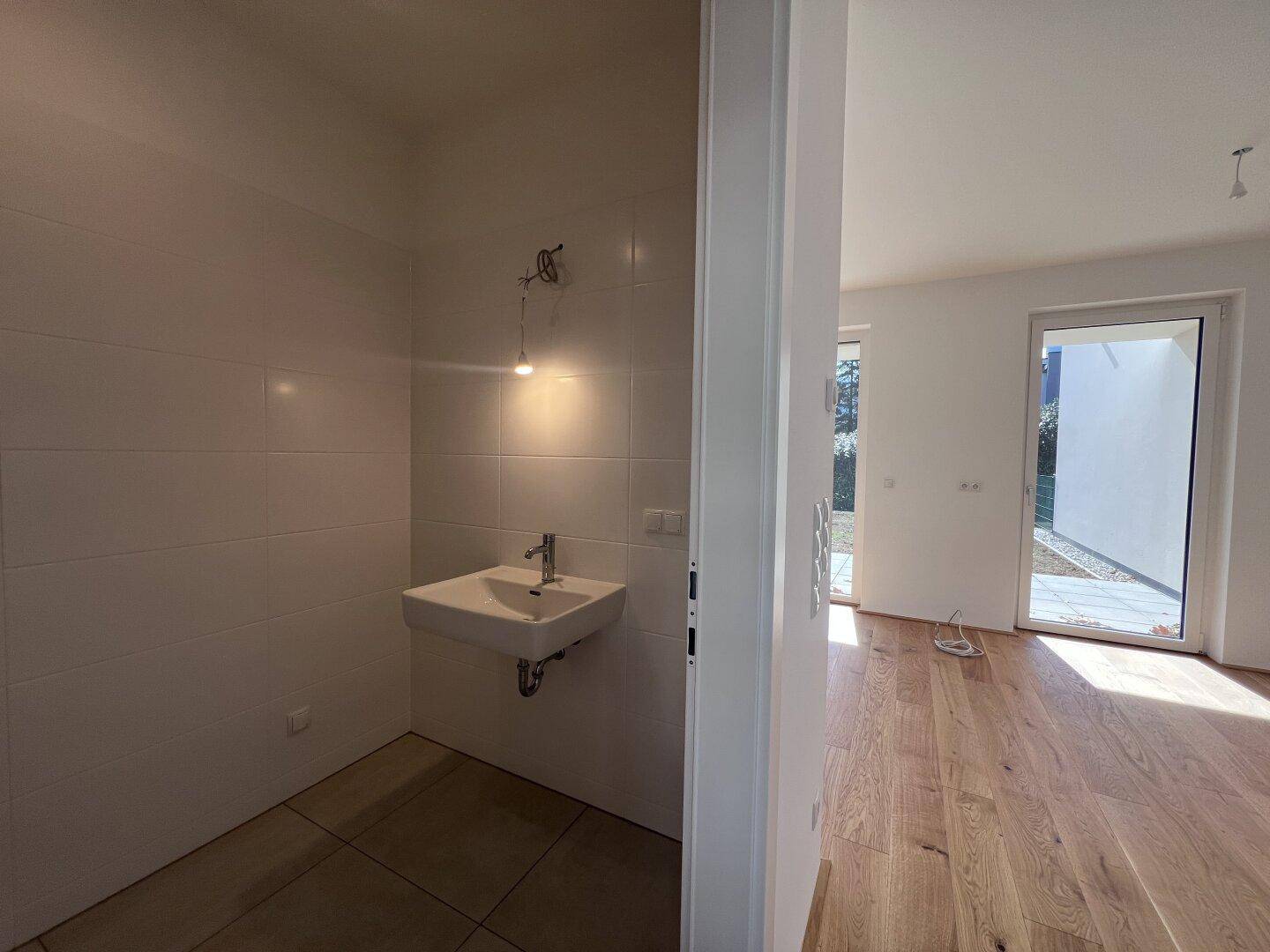 Kleines, hell gefliestes WC mit Waschbecken und moderner Ausstattung.