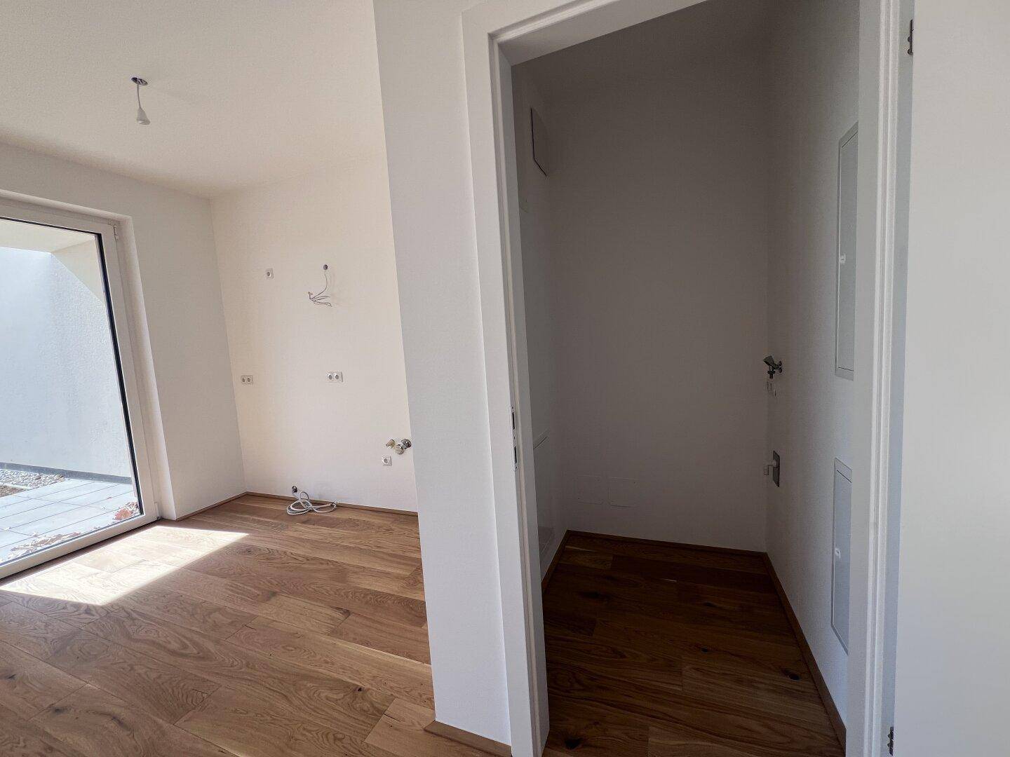 Praktischer Abstellraum mit Anschlüssen und Holzboden, ideal für Waschmaschine oder Lagerung.
