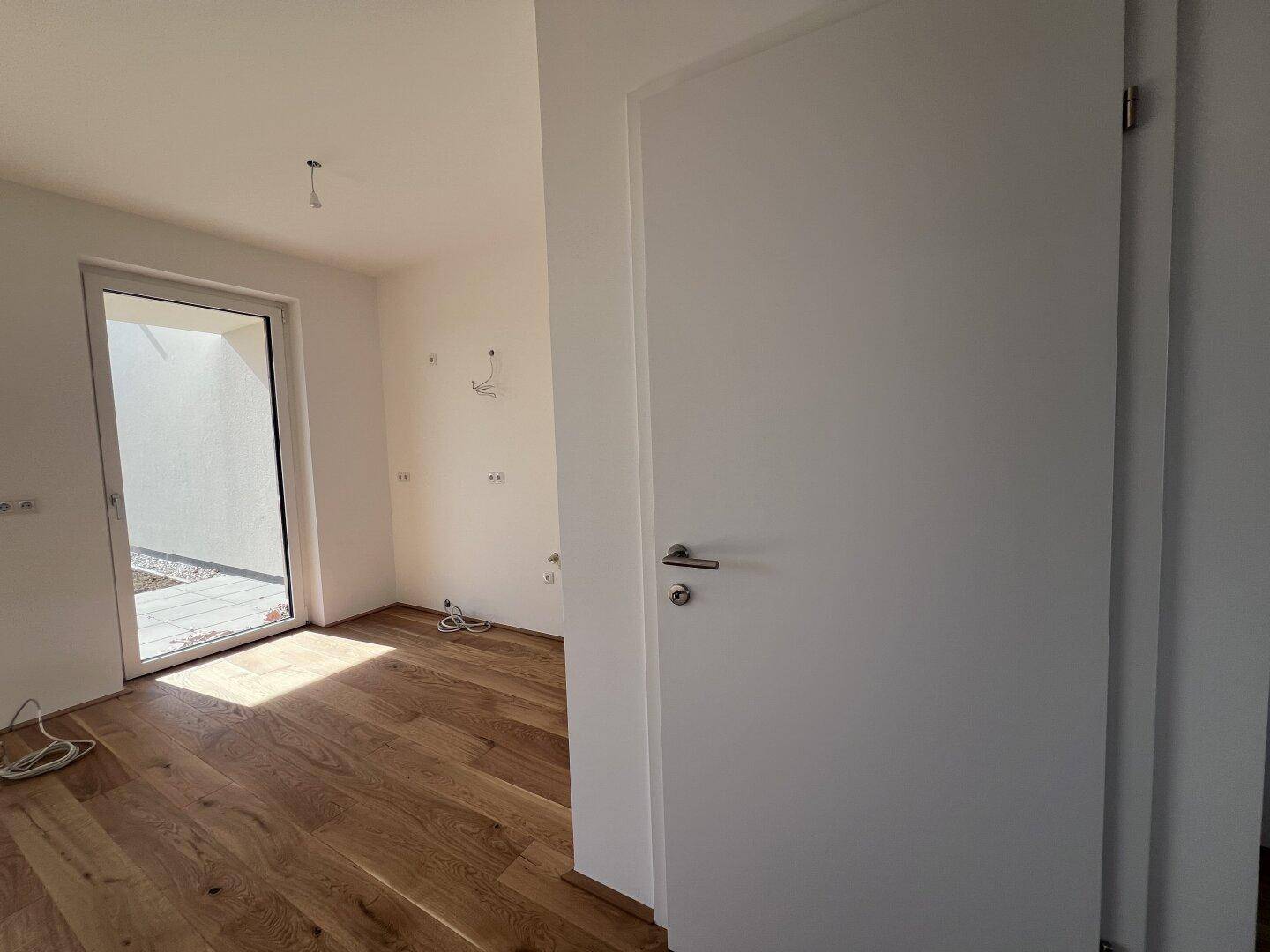 Heller Wohnbereich mit Holzboden und weißer Innentür, bereit für die Einrichtung.
