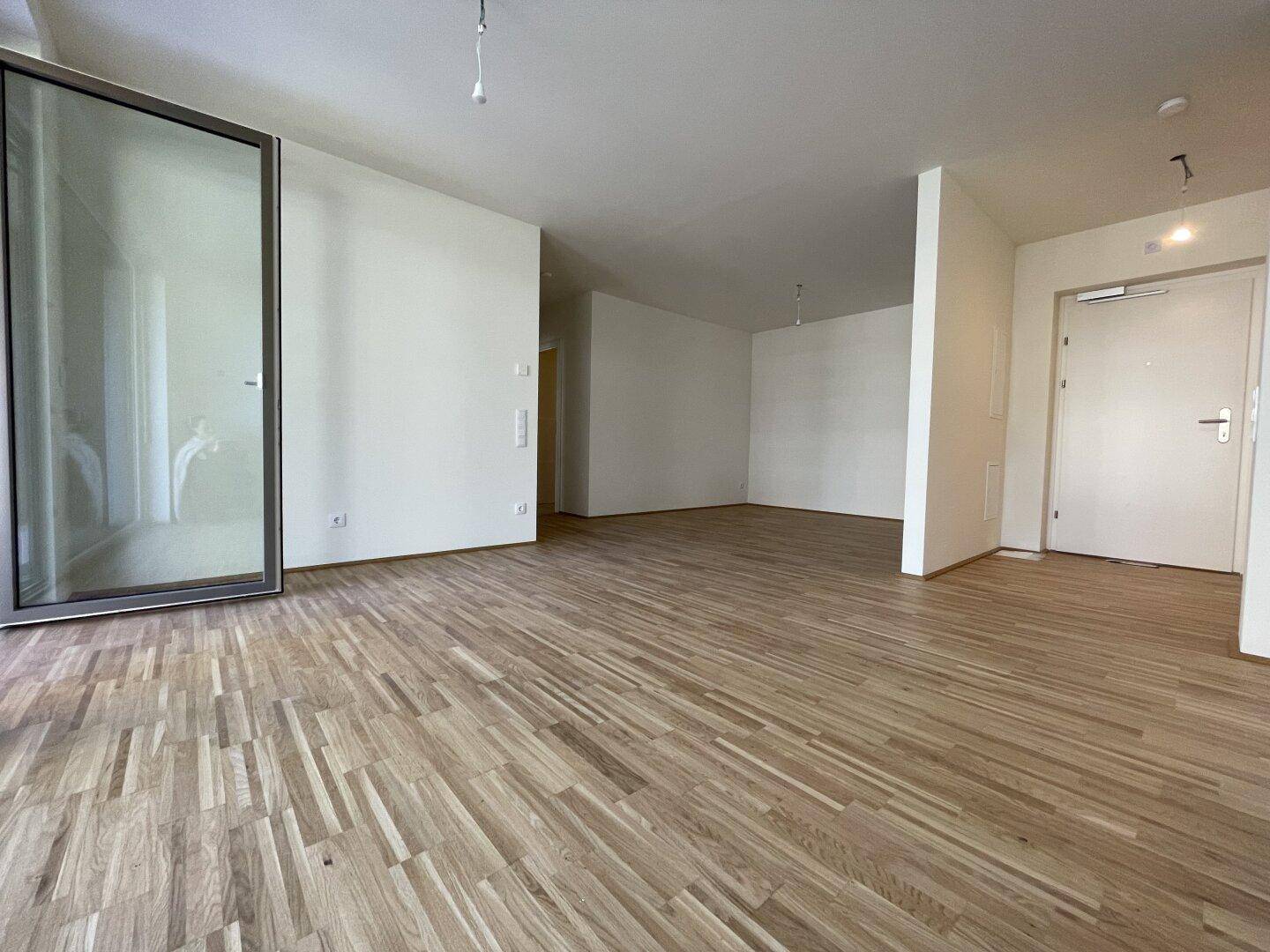Geräumiger, offener Wohnbereich mit Parkettboden und großer Glasfront für viel Tageslicht.
