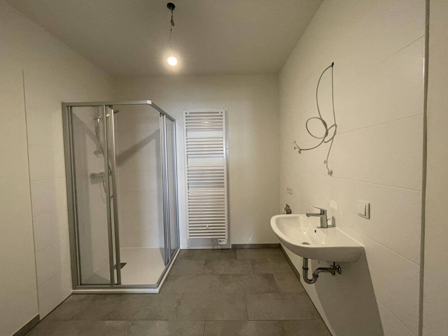 Modernes Badezimmer mit Duschkabine, Einzelwaschbecken und beheiztem Handtuchhalter.