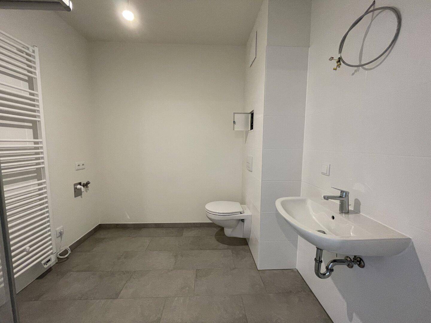Funktionales Badezimmer mit WC, Waschbecken und praktischem Handtuchheizkörper.