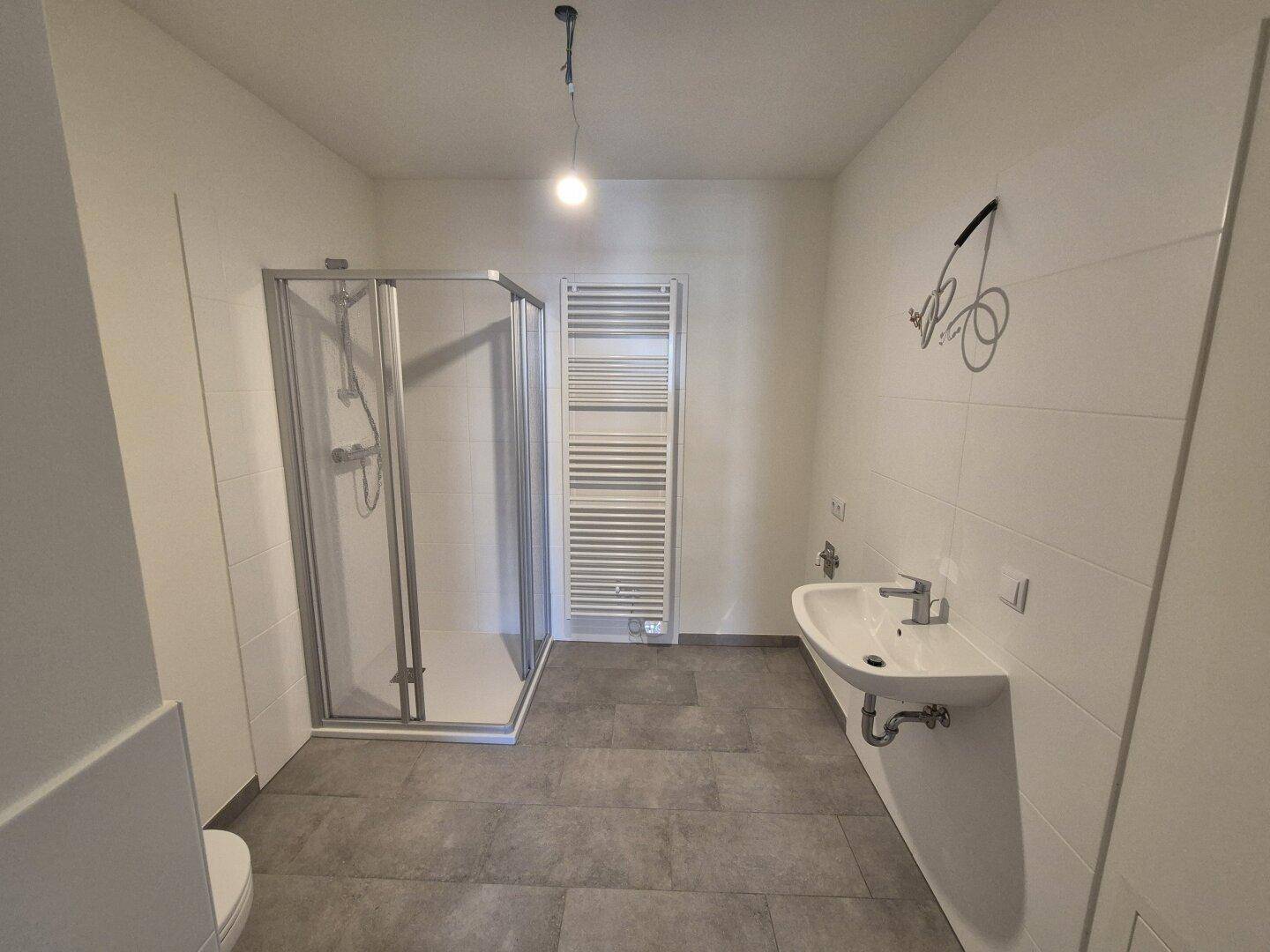 Modernes Badezimmer mit Duschkabine, Waschbecken und beheiztem Handtuchhalter.