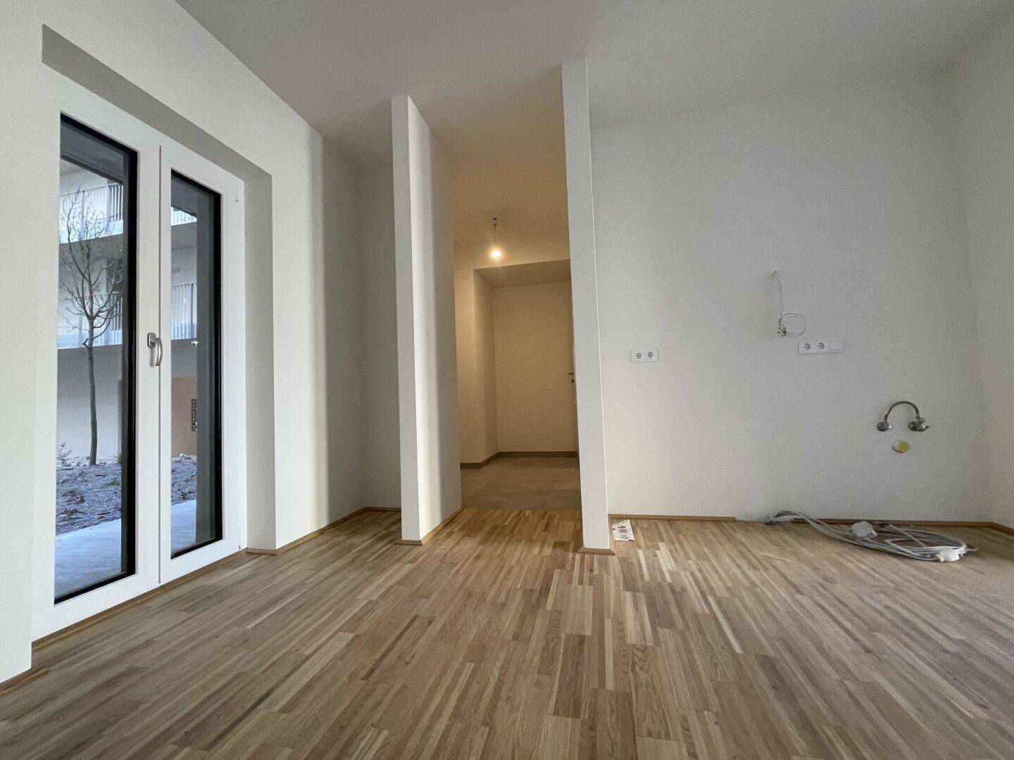 Unmöblierter Küchenbereich mit Parkettboden und Anschlüssen für eine Einbauküche.