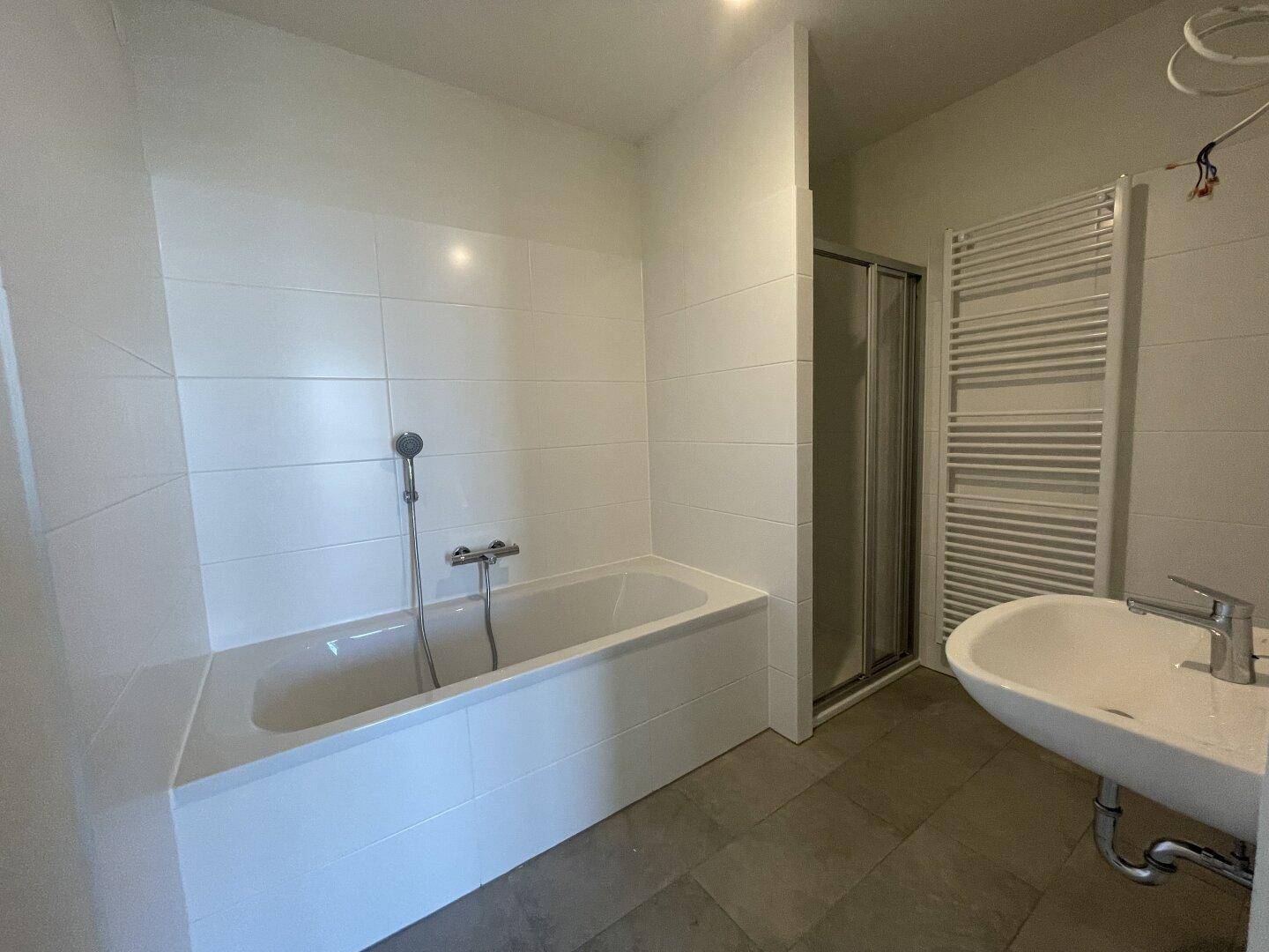 Modernes Badezimmer mit Badewanne, Duschkabine, Waschbecken und Handtuchheizkörper.