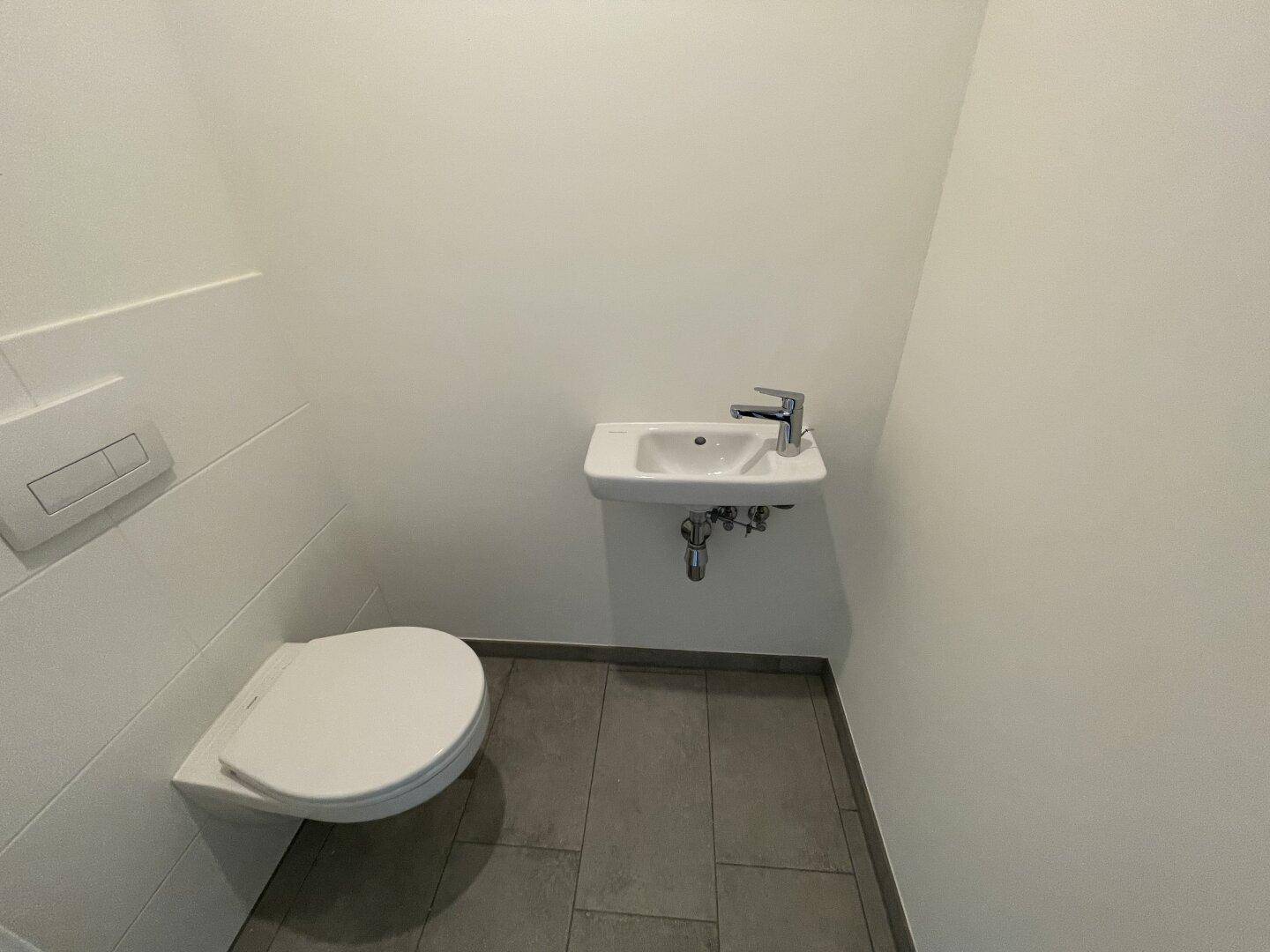 Modernes Gäste-WC mit wandhängender Toilette und kleinem Waschbecken.