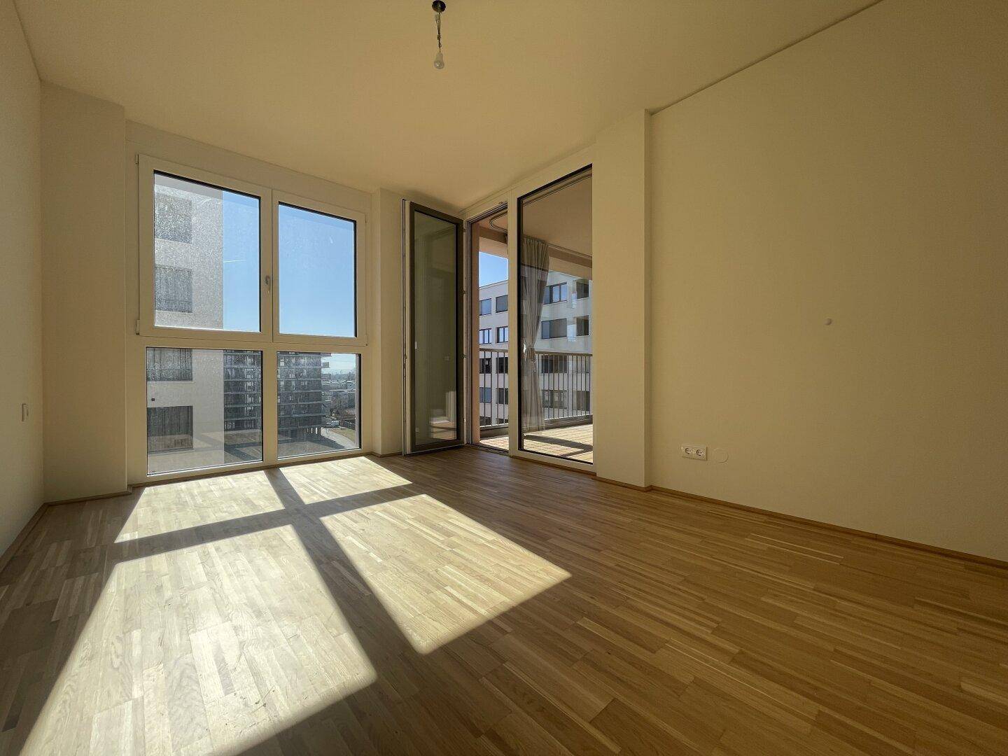 Heller Raum mit Parkettboden und Zugang zum Balkon, ideal als Schlaf- oder Wohnzimmer nutzbar.