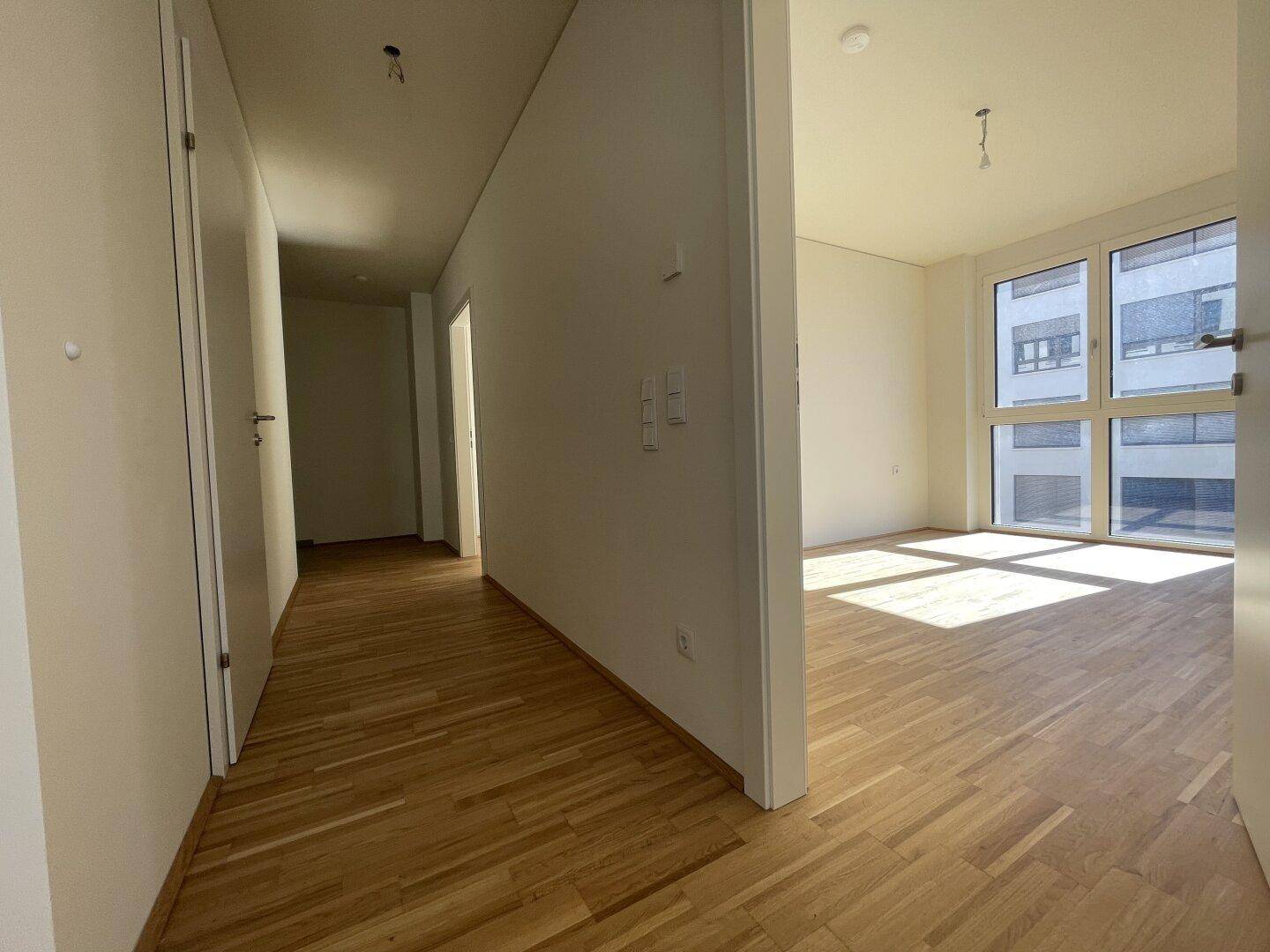 Heller Flur mit Parkettboden, der zu den verschiedenen Räumen der Wohnung führt.