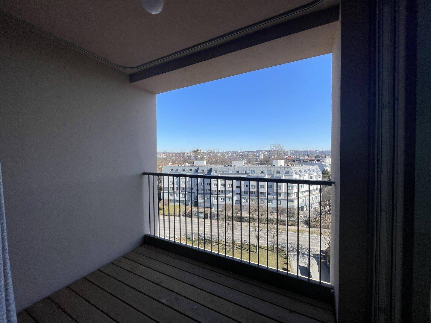Sonniger Balkon mit Blick auf die umliegende Stadtbebauung und viel Freiraum.