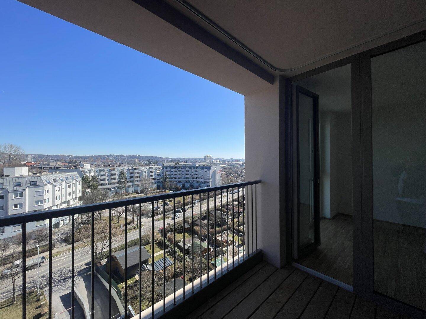 Geräumiger Balkon mit weitem Stadtblick und viel Sonnenlicht an einem klaren Tag.