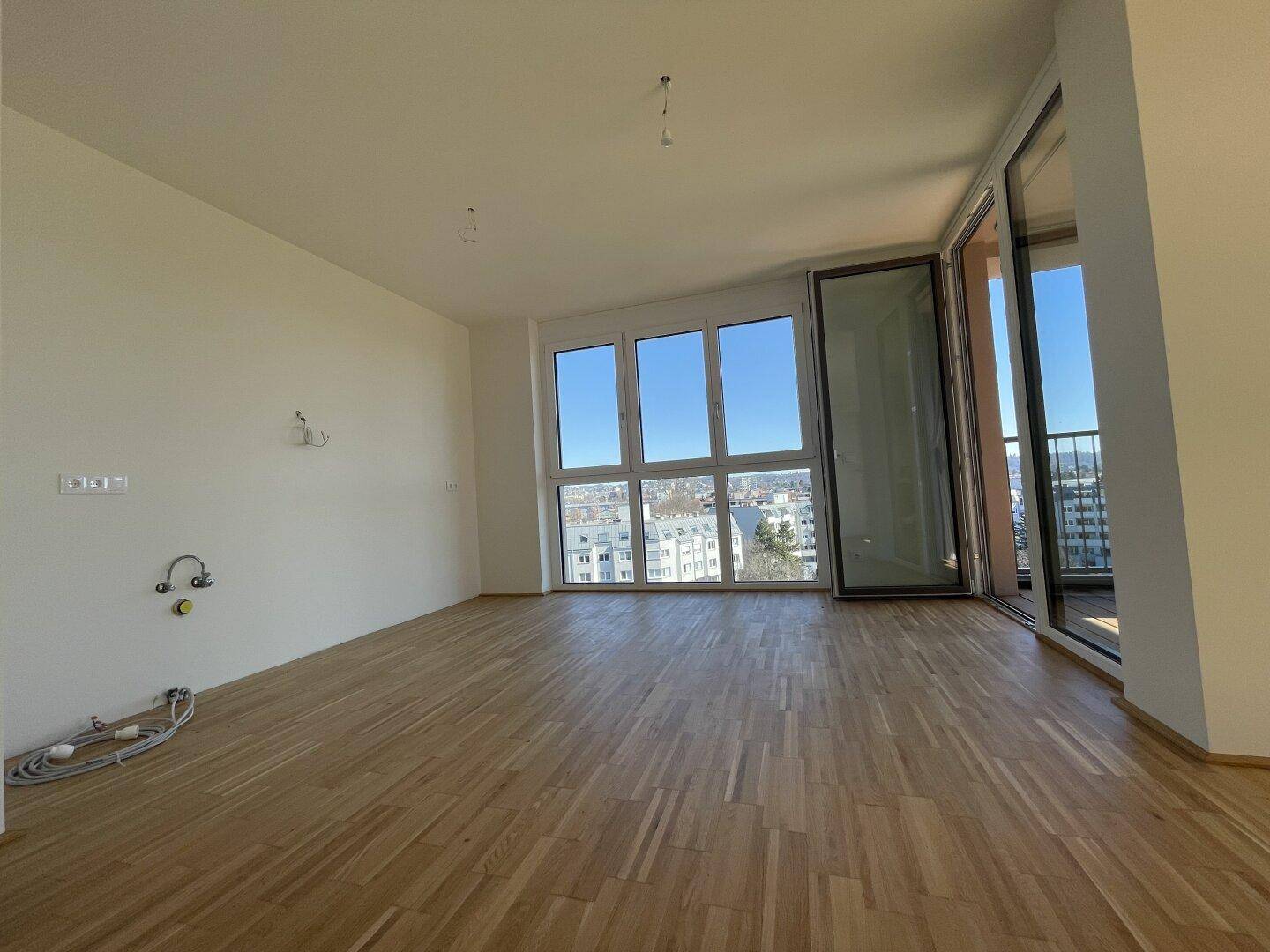 Heller Küchenbereich mit Parkettboden und Anschlüssen für eine moderne Einbauküche.