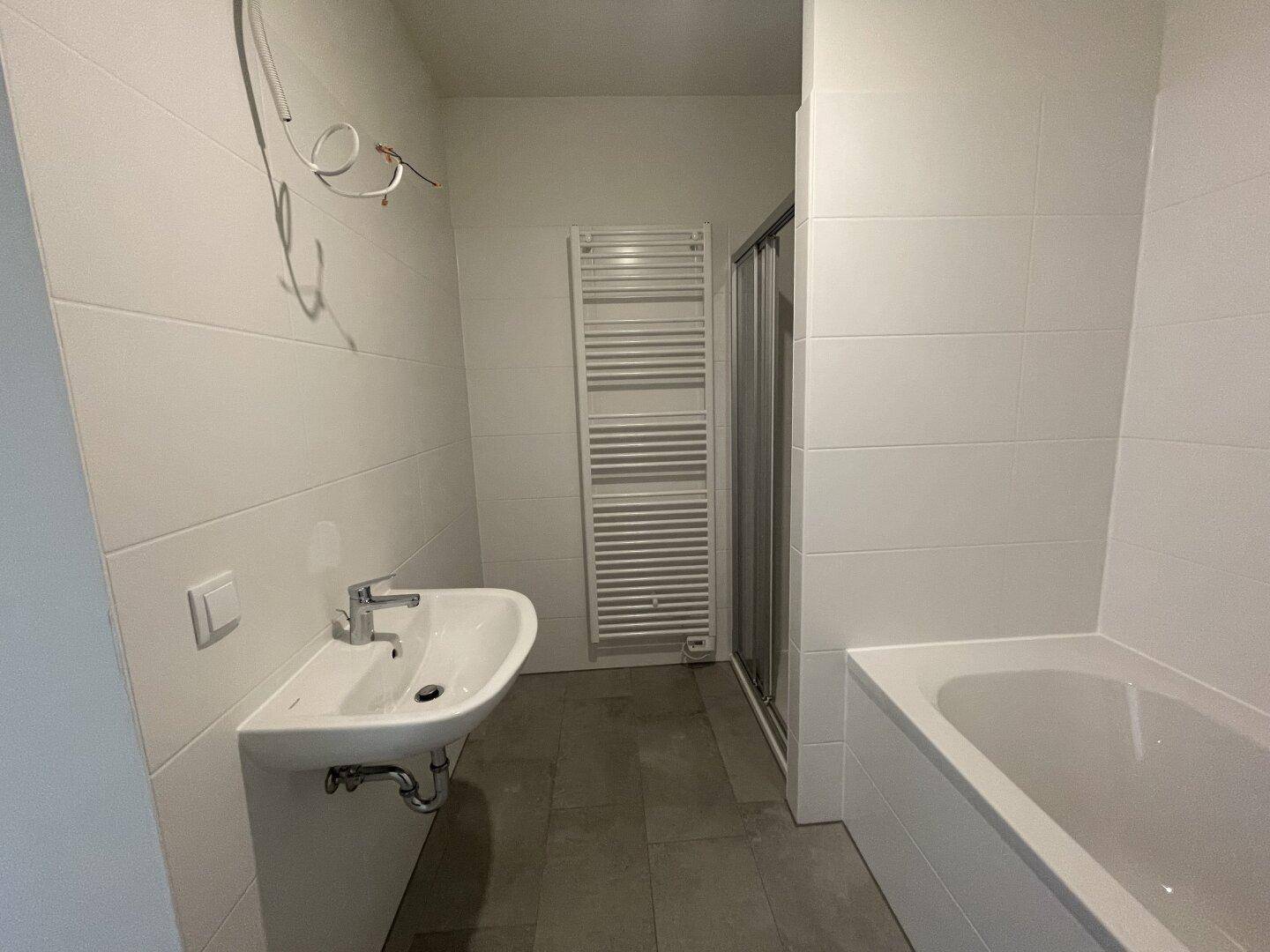 Modernes Badezimmer mit Badewanne, Dusche, Waschbecken und beheiztem Handtuchhalter.