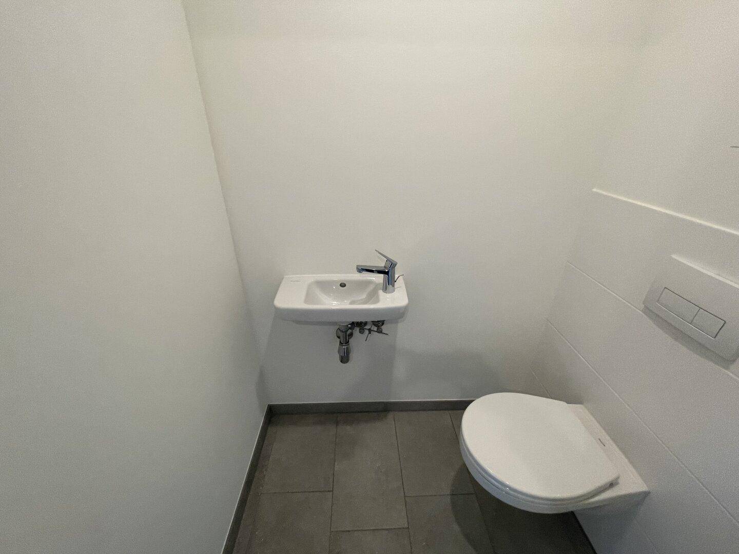 Kompaktes Gäste-WC mit modernem Wand-WC und kleinem Waschbecken.
