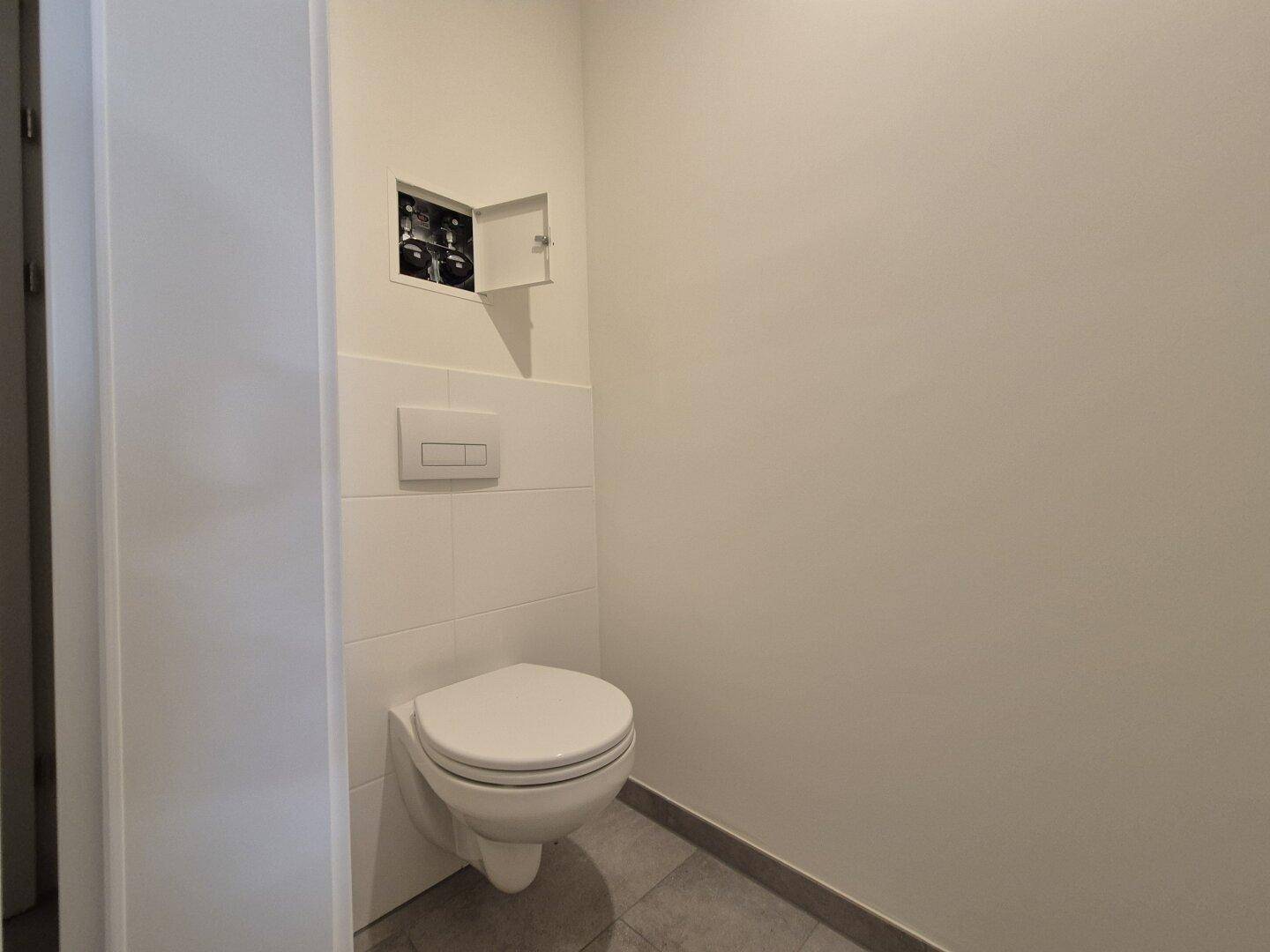 Wandhängendes WC mit moderner Spülung in einem hellen, gefliesten Raum.