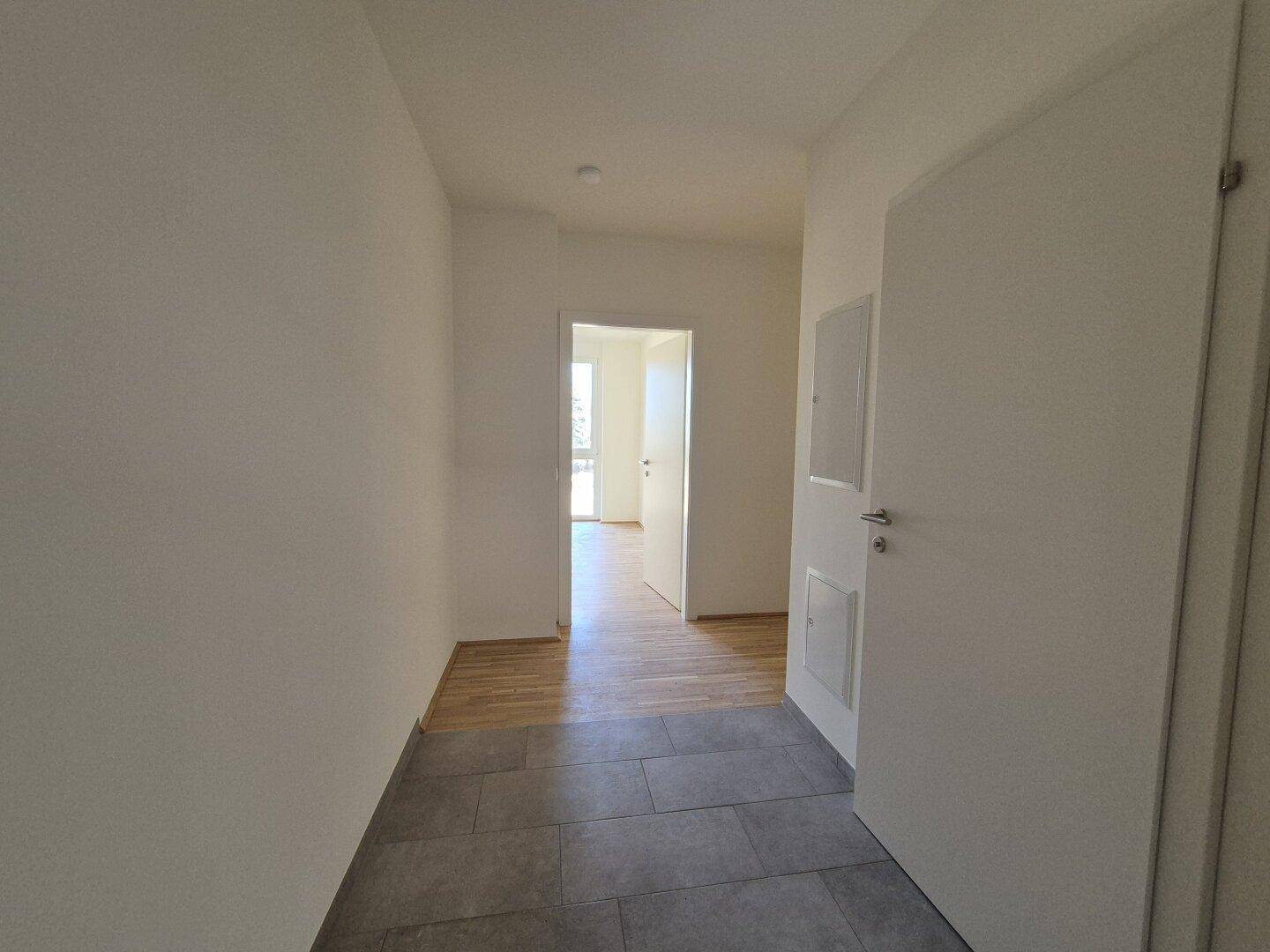 Heller Flur mit Fliesenboden im Eingangsbereich und Holzboden in den angrenzenden Räumen.