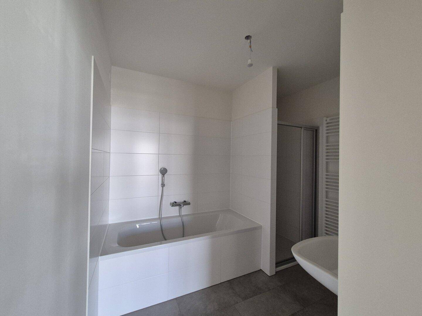 Modernes Badezimmer mit Badewanne, Duschkabine und Handtuchheizkörper.