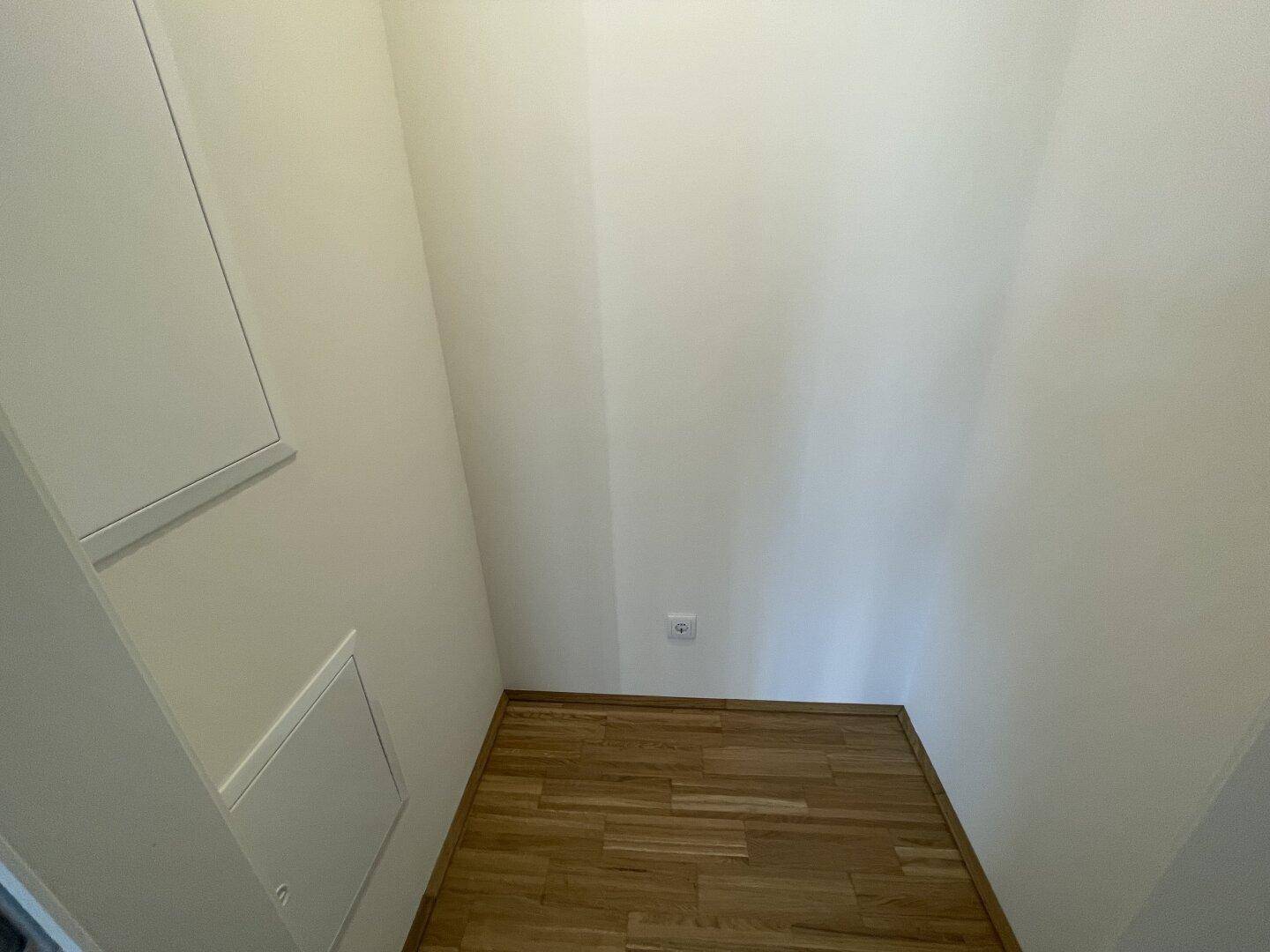 Praktischer Abstellraum mit Parkettboden und weißen Wänden für zusätzlichen Stauraum im Haushalt.