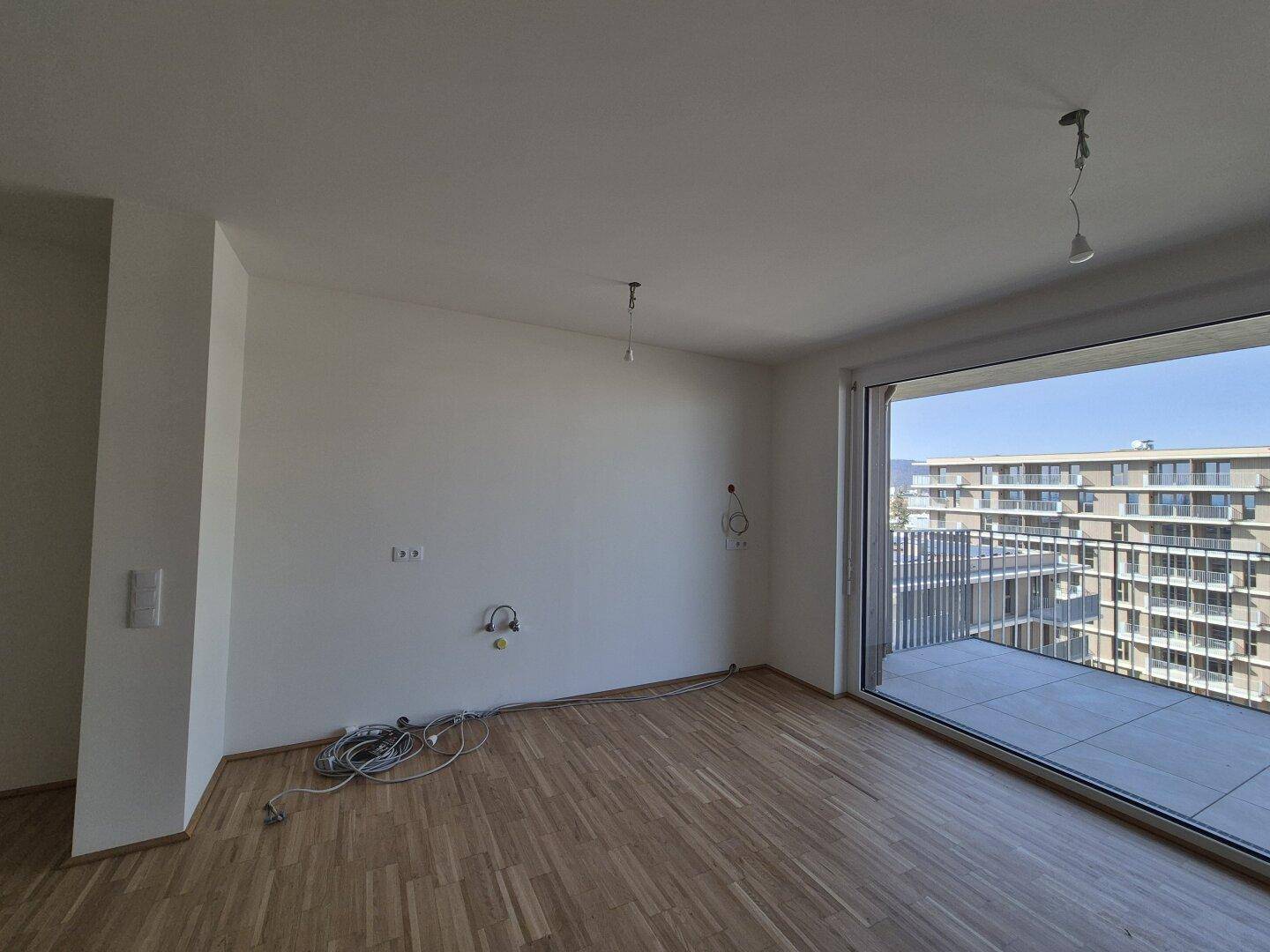 Heller Wohnbereich mit großem Schiebefenster und direktem Zugang zu einer geräumigen Terrasse.